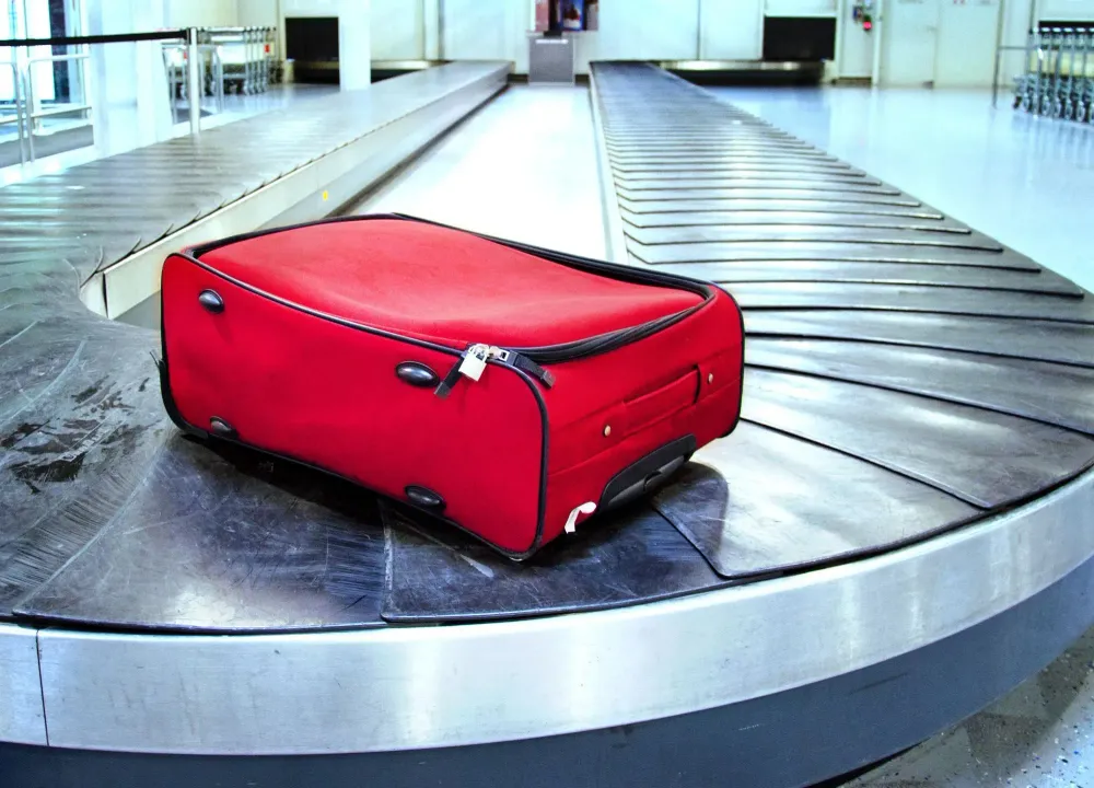 Single red suitcase on an otherwise empty baggage carousel